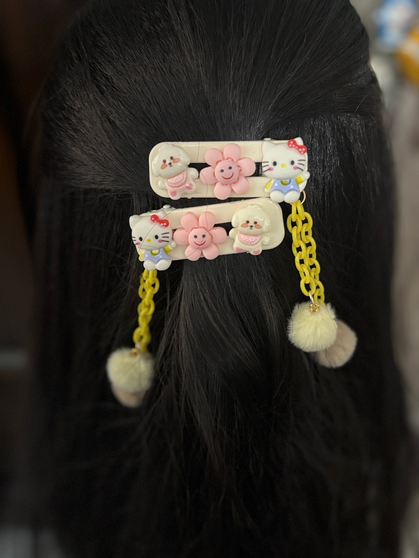 Pastel hair clips with Hello Kitty, happy flowers, a tiny bear, yellow chains, and fluffy Pom Poms. Perfect for adding charm to any hairstyle or outfit.