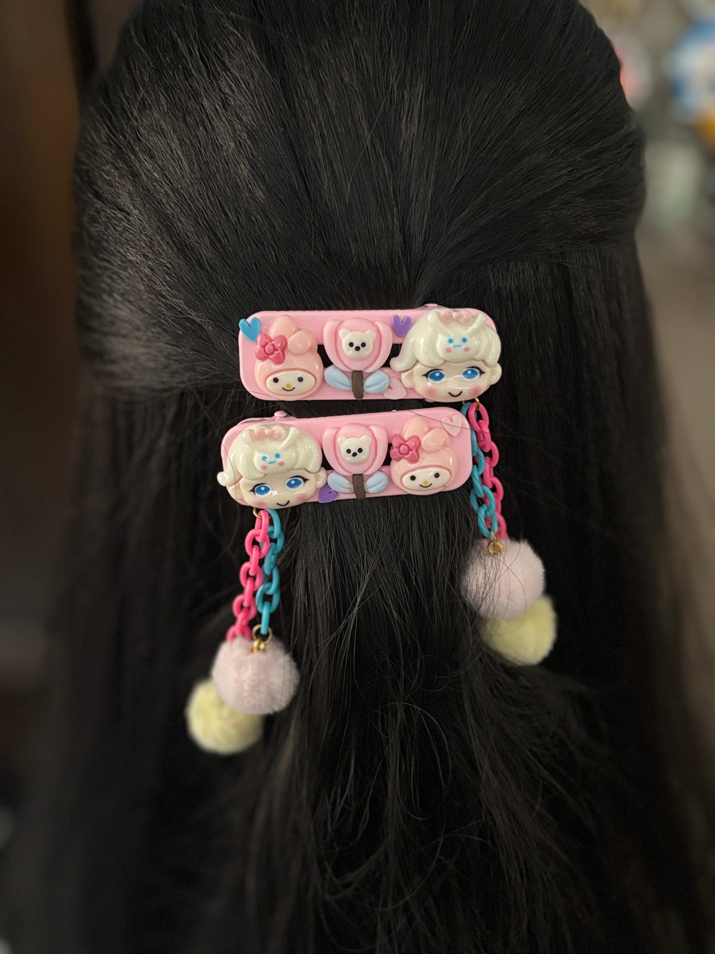 Set of My Melody-themed hair clips with pink and blue chains, fuzzy pom pom dangles, and cute cartoon faces—ideal for playful, fun hairstyles for kids.