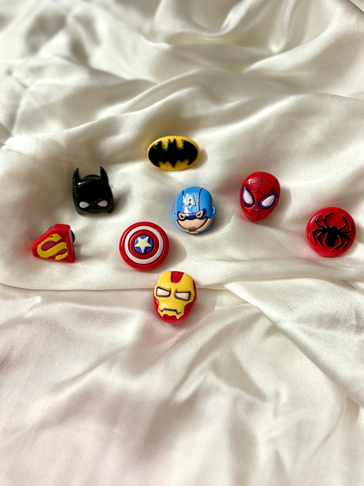 Black Crocs decorated with superhero-themed Jibbitz charms including Spider-Man, Iron Man, Captain America, Batman, and Superman icons.