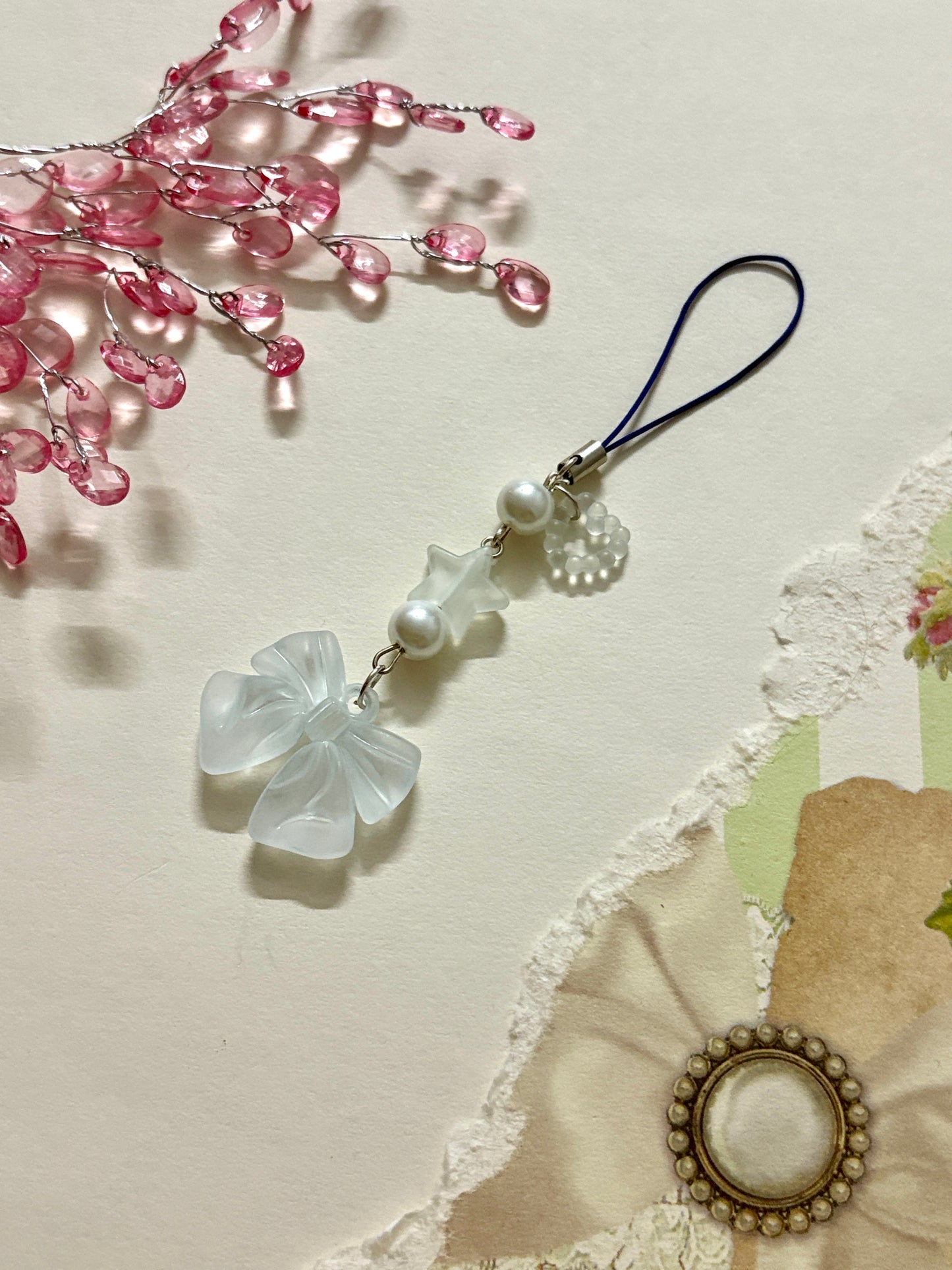 Elegant phone charm with a frosted white bow, faux pearls, star bead, and delicate accents. A light, dreamy accessory for phones, bags, or keychains.
