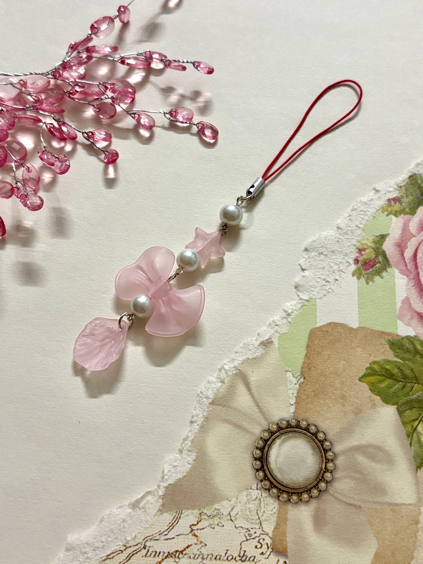 Phone charm featuring a translucent bow, star bead, faux pearls, and a leaf charm. A light, elegant accessory perfect for phones, bags, or keychains.
