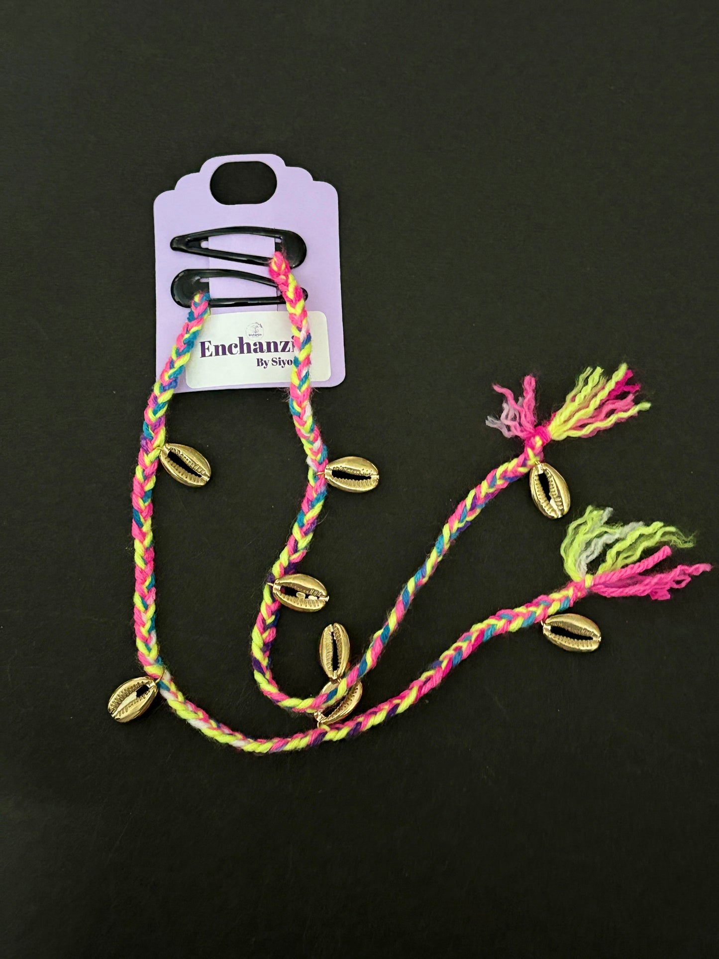 A vibrant neon-colored Goa-style hair braid featuring braided threads in bright pink, yellow, and blue, decorated with metallic cowrie shells and styled into natural hair for a fun, beachy look.