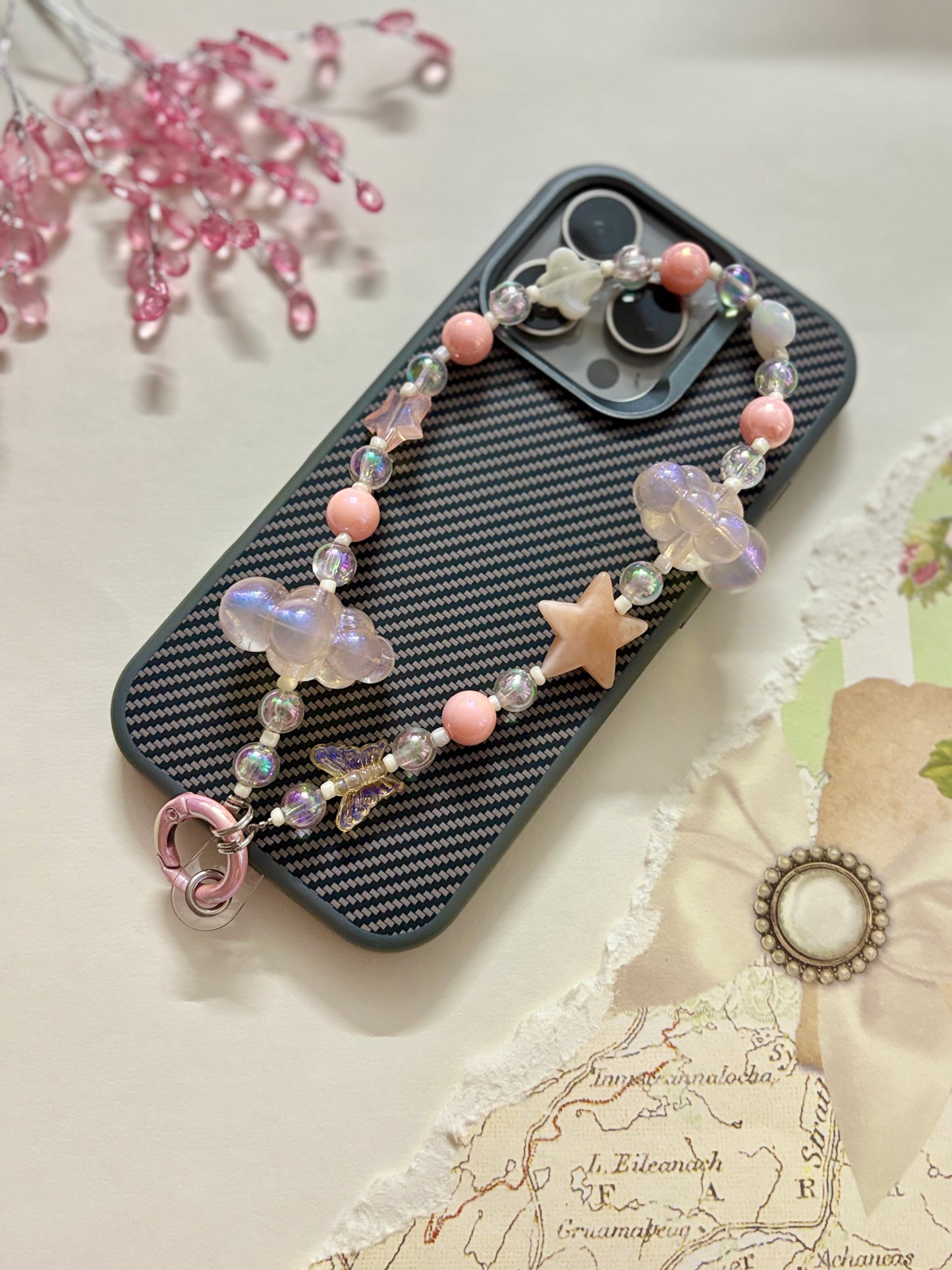 Aesthetic beaded phone charm featuring translucent clouds, a navy star, pastel beads, and butterfly accents, arranged in a dreamy celestial theme.