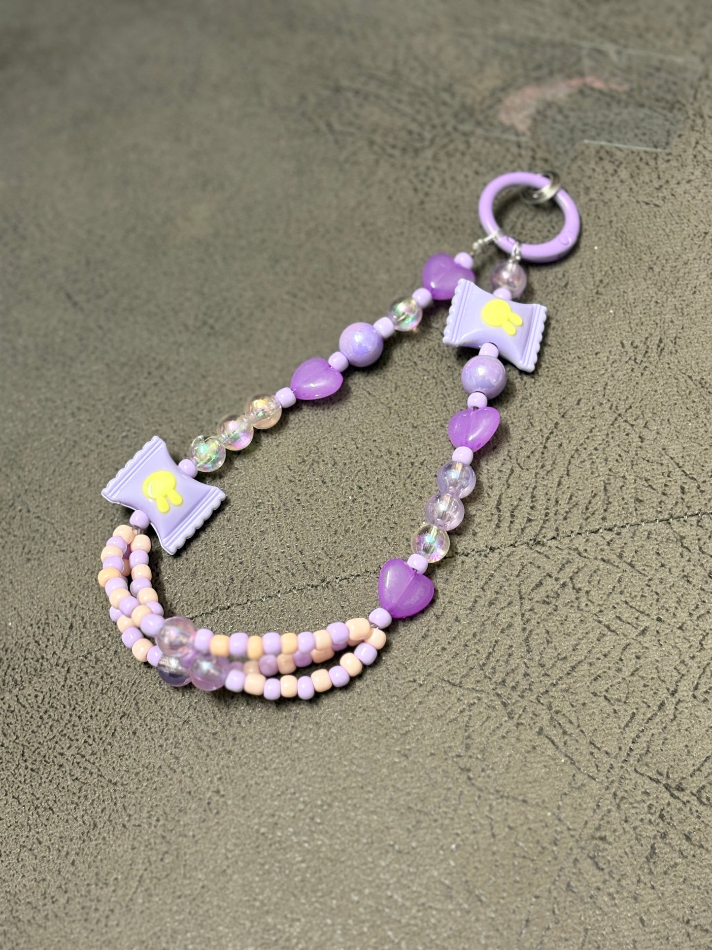 A set of handmade beaded phone charms featuring playful candy-shaped accents, heart beads, and glossy finishes, designed to accessorize phone cases with a fun and trendy touch.