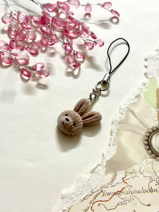 Soft brown plush bunny phone charm with black strap, cute face, and velvet texture. Aesthetic animal accessory for phone, bag, or keyring use.
