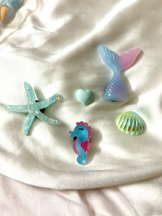 Set of 5 pastel ocean Crocs Jibbitz charms featuring a mermaid tail, glitter starfish, cute seahorse, seashell, and heart—perfect for a soft beachy vibe.