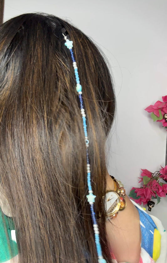 A handmade bohemian-style hair braid decorated with small beads and shaped charms, clipped into natural hair for a free-spirited, festival-ready look.
