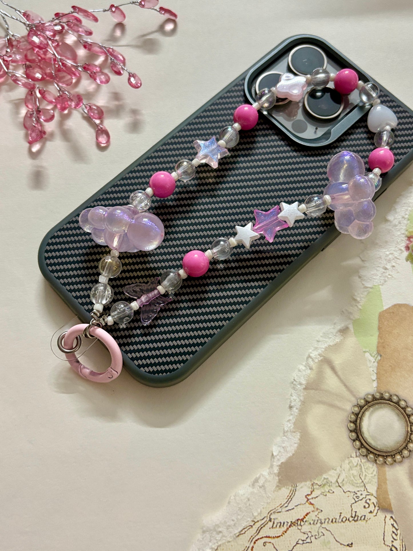Aesthetic beaded phone charm featuring translucent clouds, a navy star, pastel beads, and butterfly accents, arranged in a dreamy celestial theme.