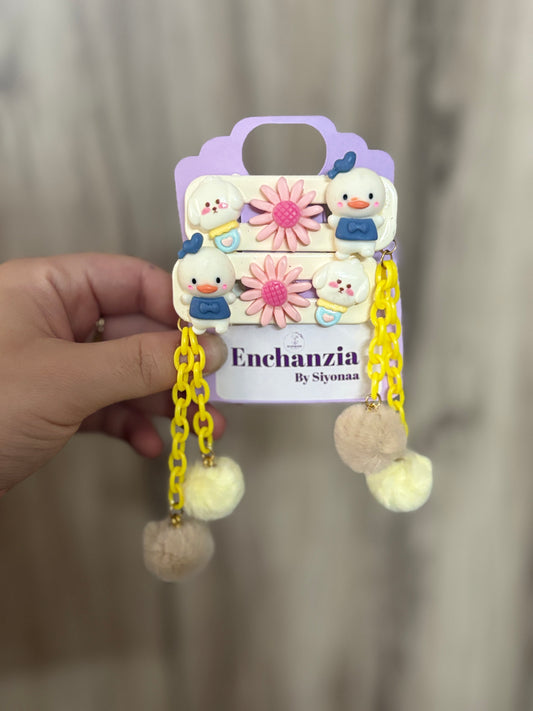 A pair of cute hair clips featuring Donald Duck, pink flowers, yellow plastic chains, and fuzzy pom pom dangles—fun and playful cartoon hair accessory.