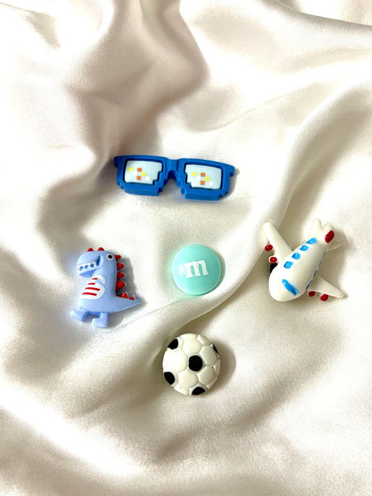 Set of 5 boys-themed Crocs Jibbitz including airplane, football, candy, dinosaur & pixel glasses. Colors may vary as assorted pieces will be sent.