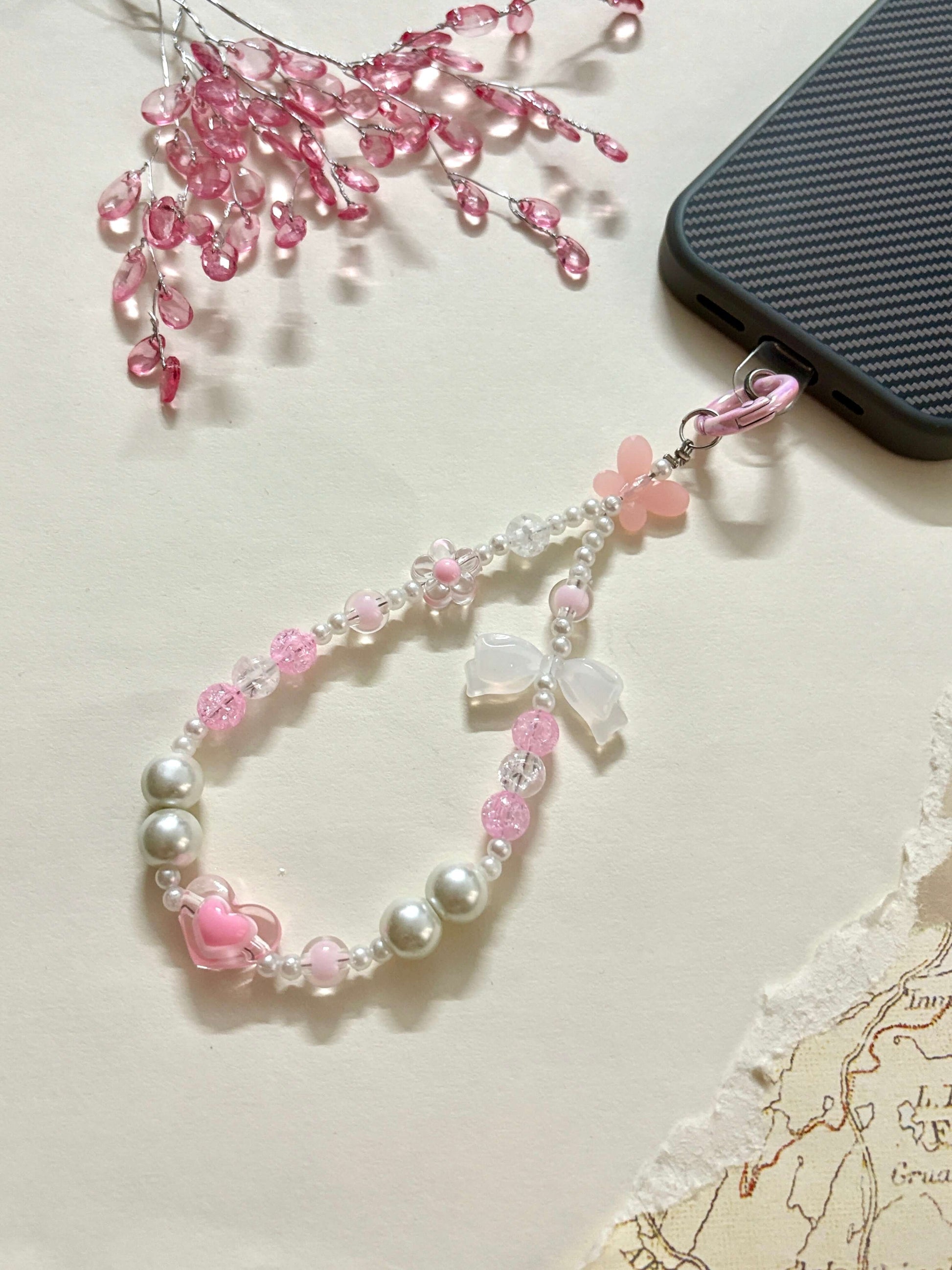 Decorative beaded phone charm featuring heart, flower, and pearl-like beads with a mix of textures and finishes, designed as a stylish phone strap accessory.