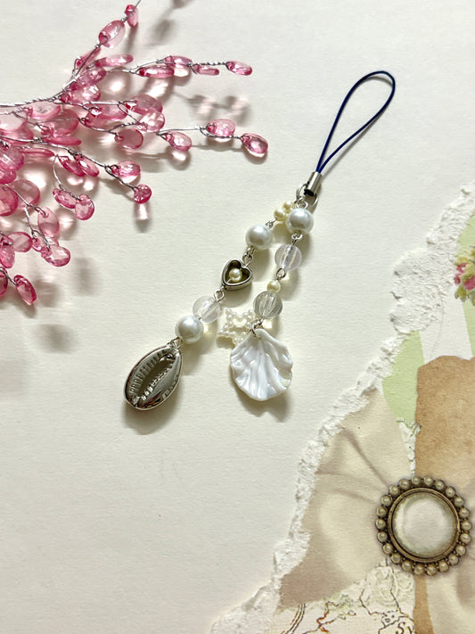White pearl and shell phone charm with heart, beads, and ocean-inspired design. A cute and trendy phone accessory for beachy, minimal, or aesthetic styles.
