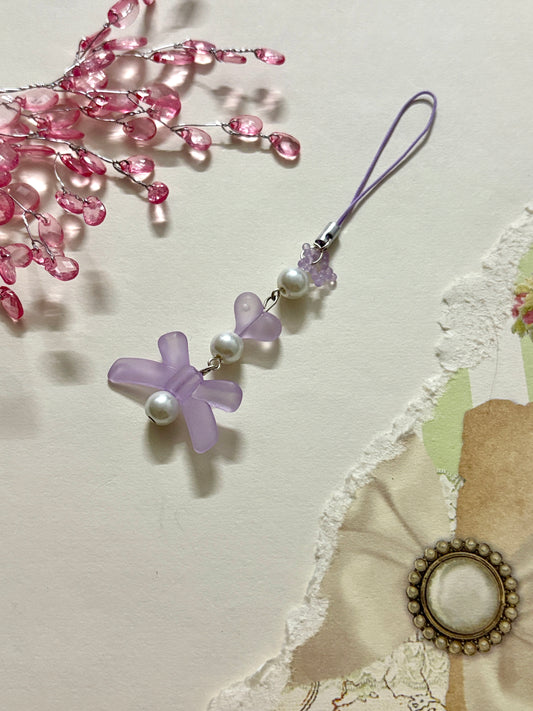Frosted lavender phone charm with bow, faux pearls, matte heart bead, and delicate textured accent. A cute pastel accessory for phones and keychains.