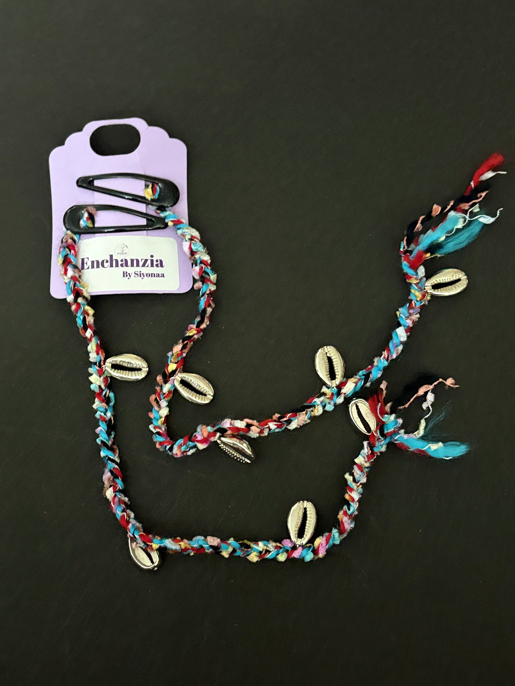 A vibrant handmade Goa-style hair braid woven with colorful threads and adorned with cowrie shells, braided into natural hair for a beachy, travel-inspired look.