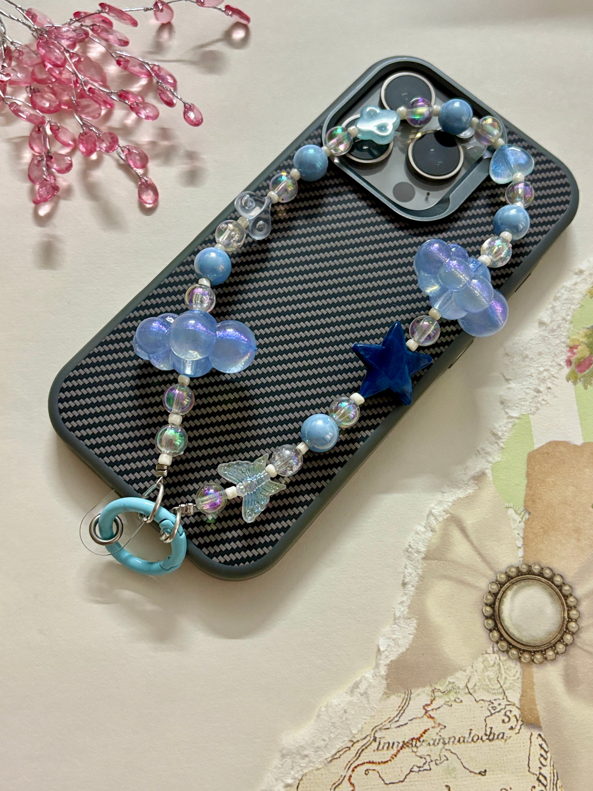 Aesthetic beaded phone charm featuring translucent clouds, a navy star, pastel beads, and butterfly accents, arranged in a dreamy celestial theme.