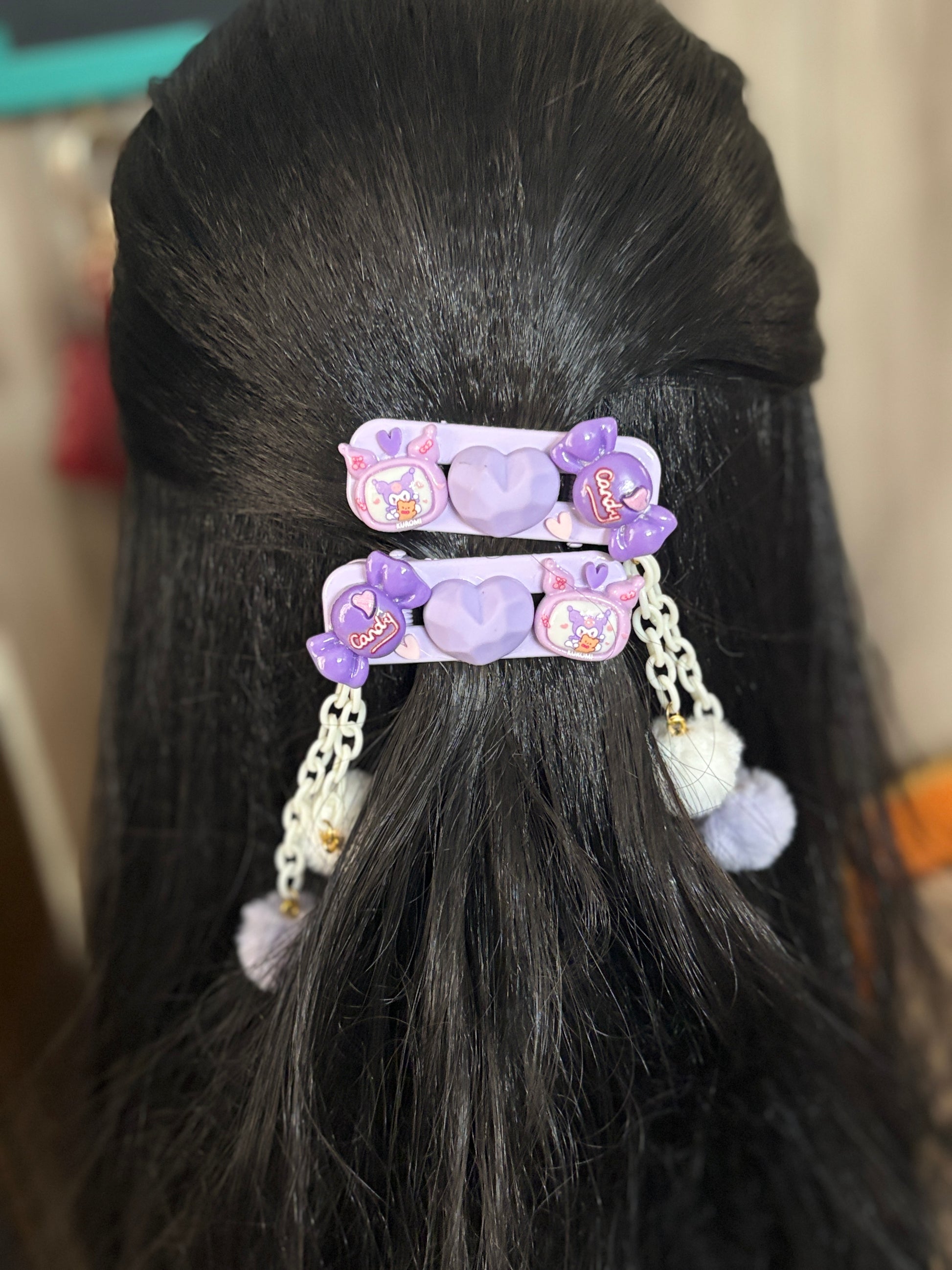 Set of purple kawaii Kuromi hair clips with heart, candy, and Kuromi designs. Decorated with chains and fluffy pom-poms. Fun accessory from Enchanzia by Siyonaa.