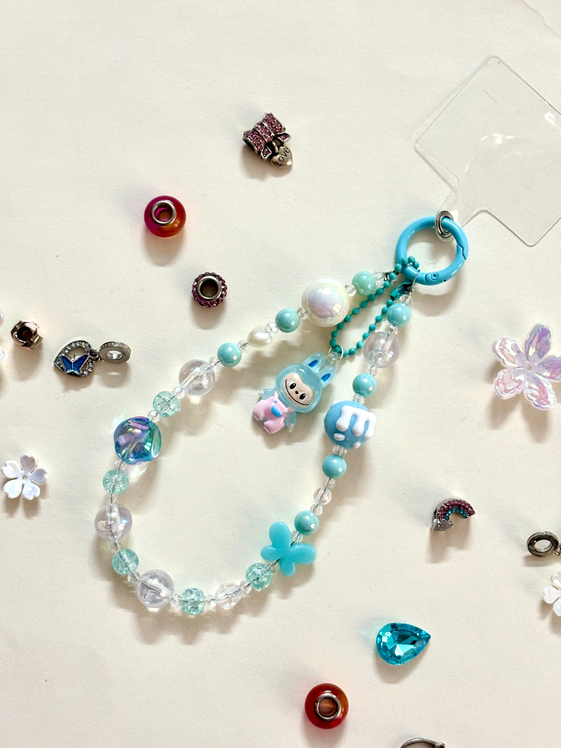 Close-up of a blue Labubu phone charm strap featuring clear and glitter beads, butterfly detail, and the rare Labubu figure — now available in three colors.