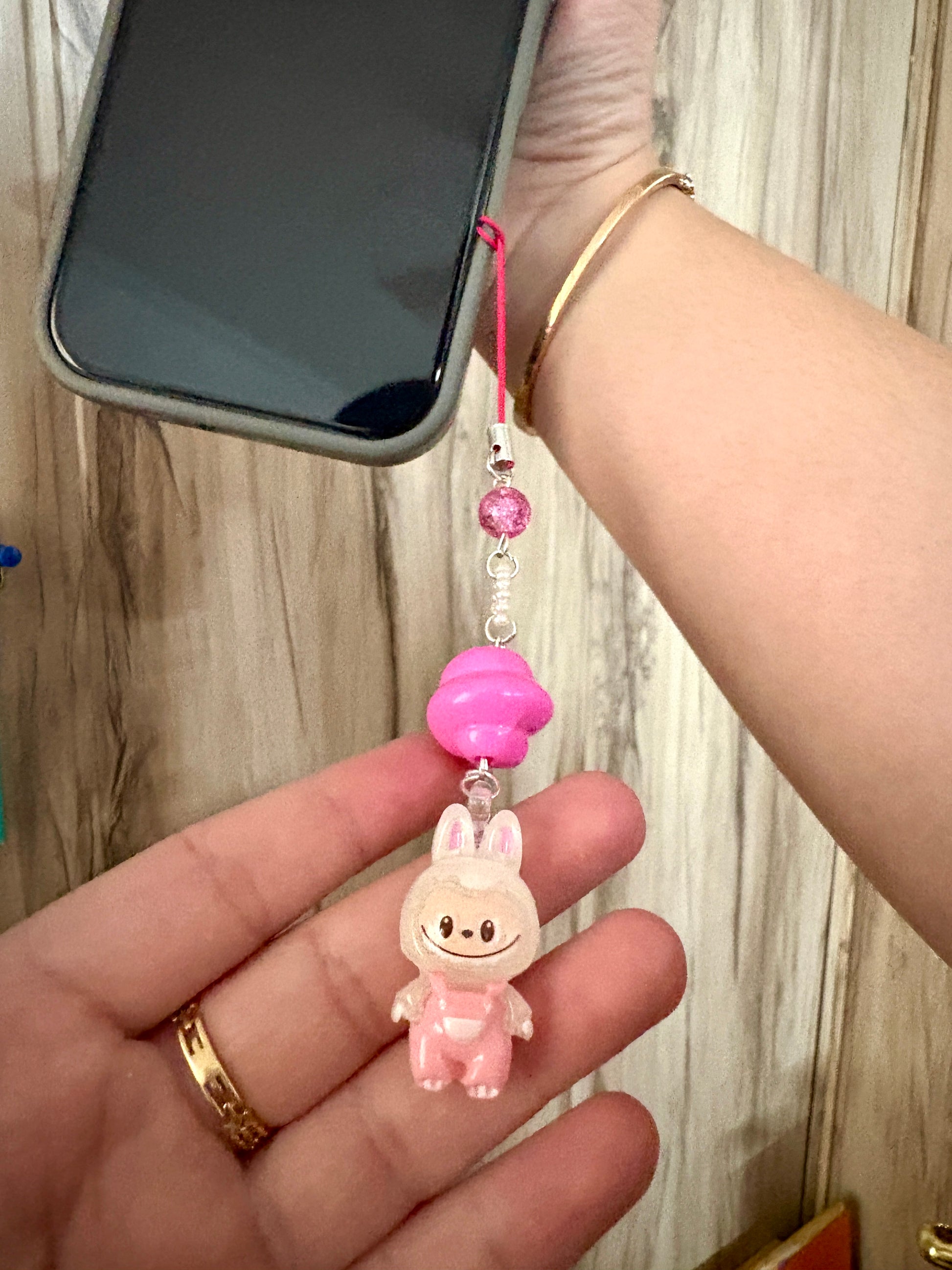 Mini Labubu phone charm with rainbow orb bead and black strap, featuring Labubu in blue overalls — collectible strap available in two color options.
