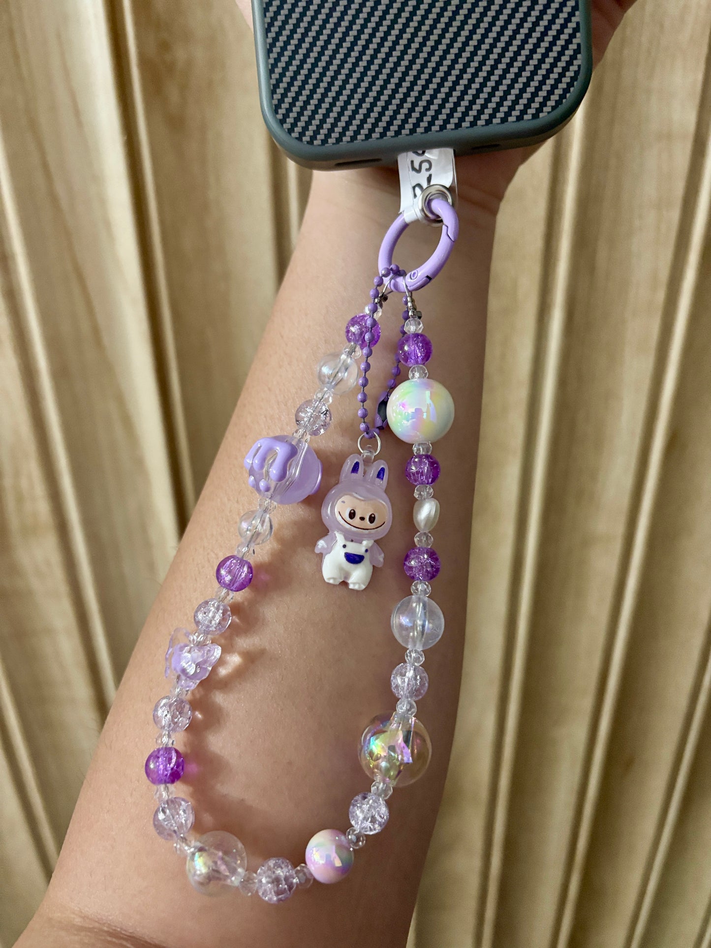 Close-up of a pink Labubu phone charm strap featuring clear and glitter beads, butterfly detail, and the rare Labubu figure — now available in three colors.