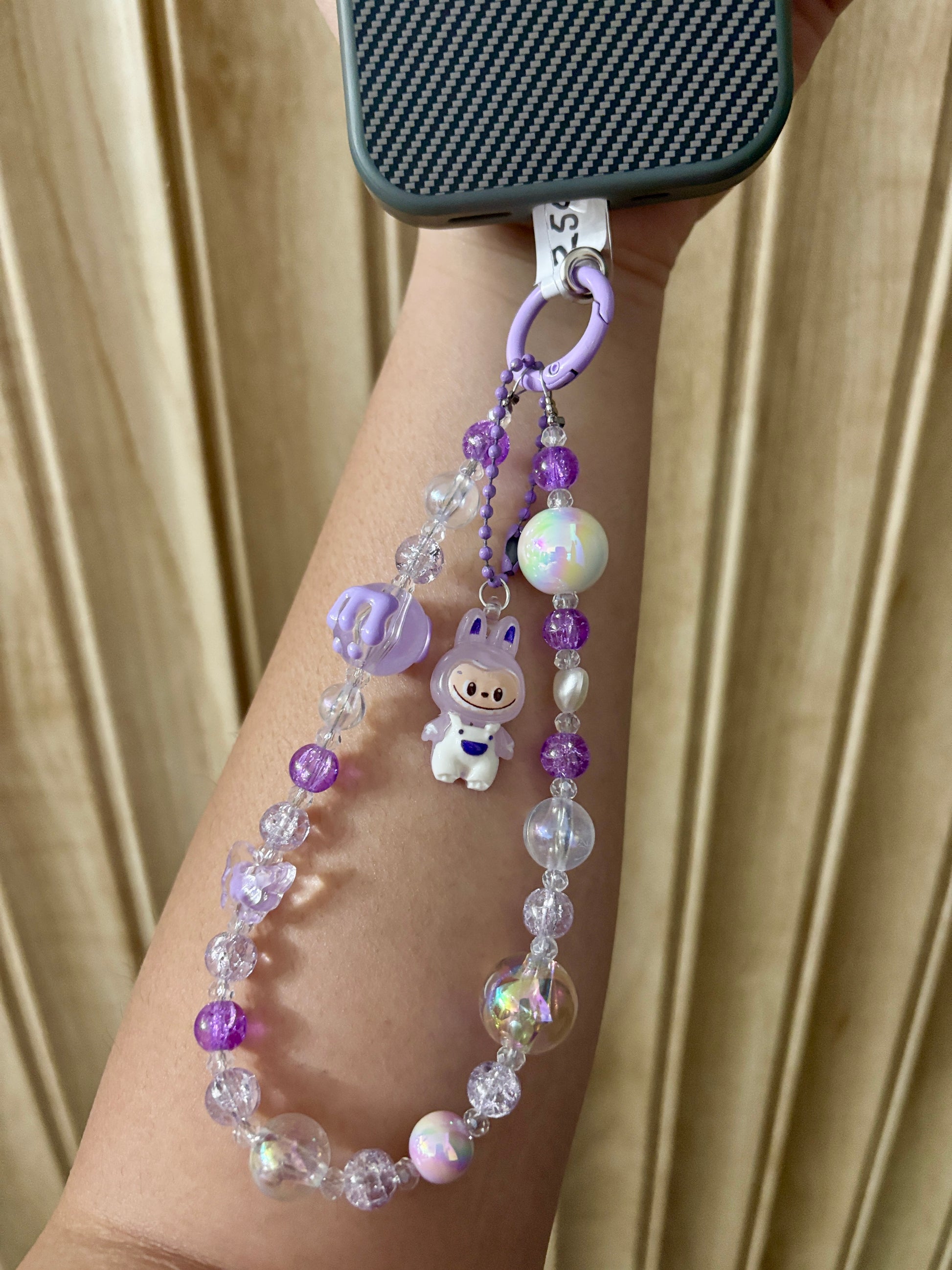 Close-up of a pink Labubu phone charm strap featuring clear and glitter beads, butterfly detail, and the rare Labubu figure — now available in three colors.