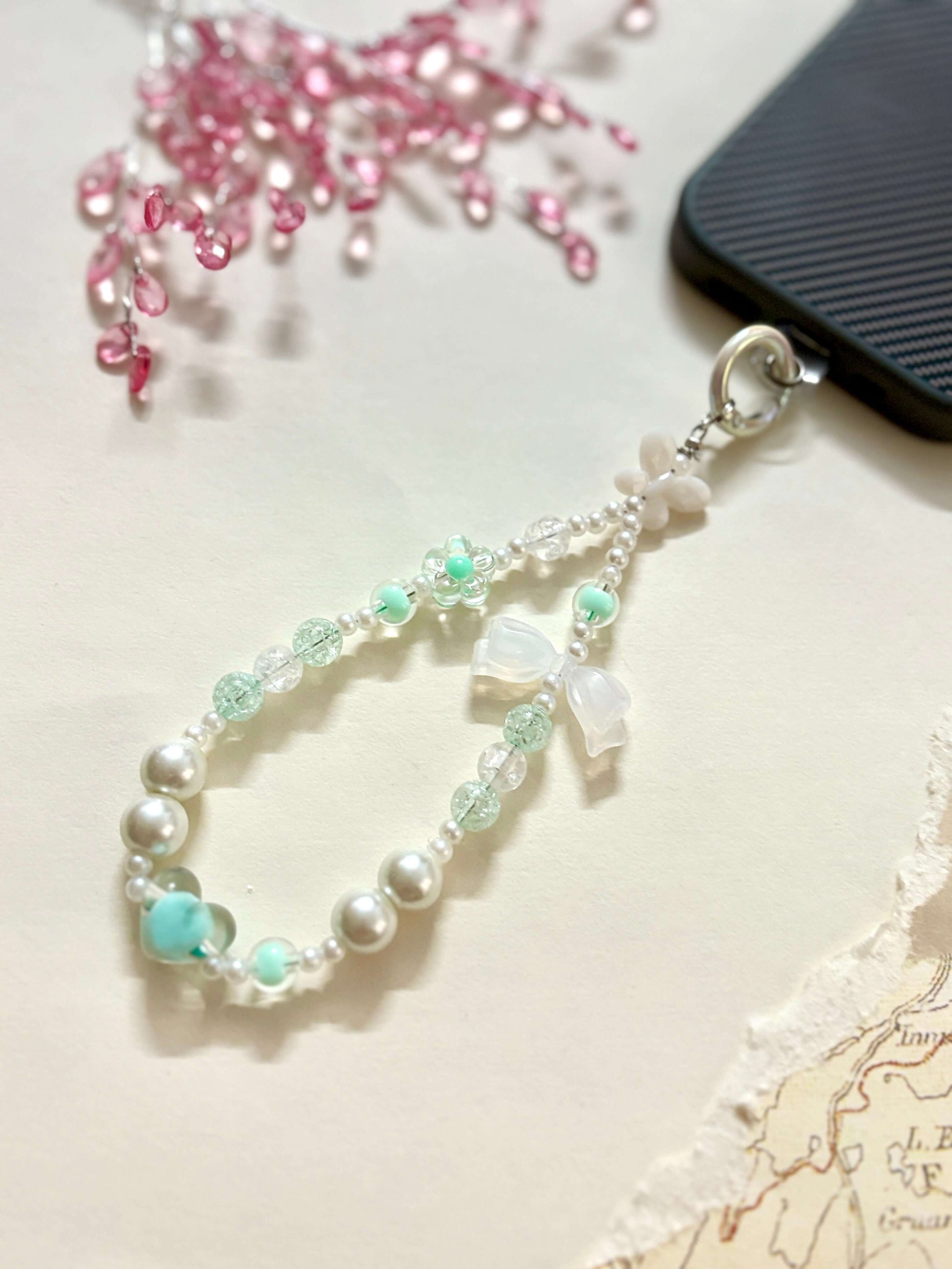 Decorative beaded phone charm featuring heart, flower, and pearl-like beads with a mix of textures and finishes, designed as a stylish phone strap accessory.