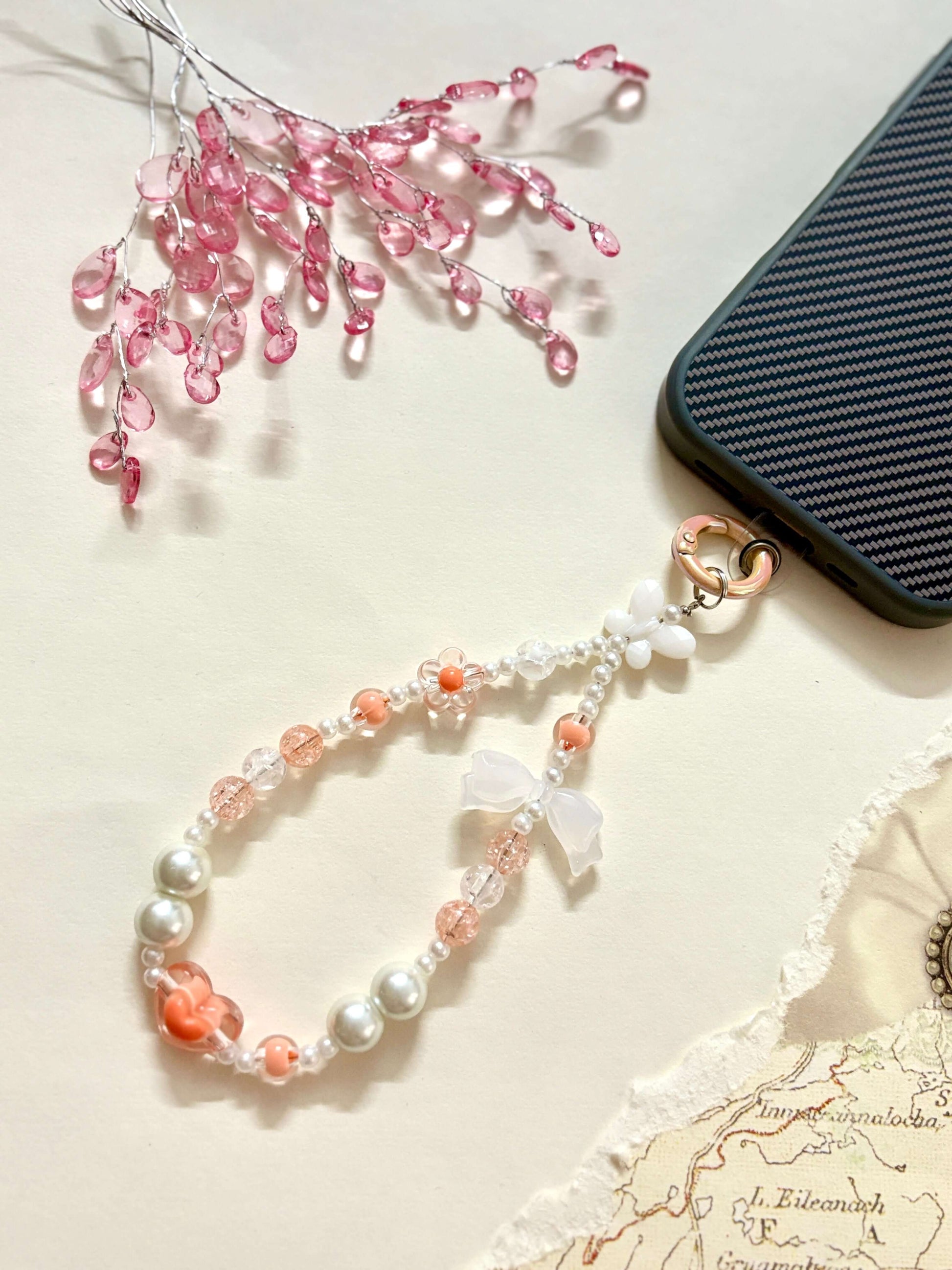 Decorative beaded phone charm featuring heart, flower, and pearl-like beads with a mix of textures and finishes, designed as a stylish phone strap accessory.