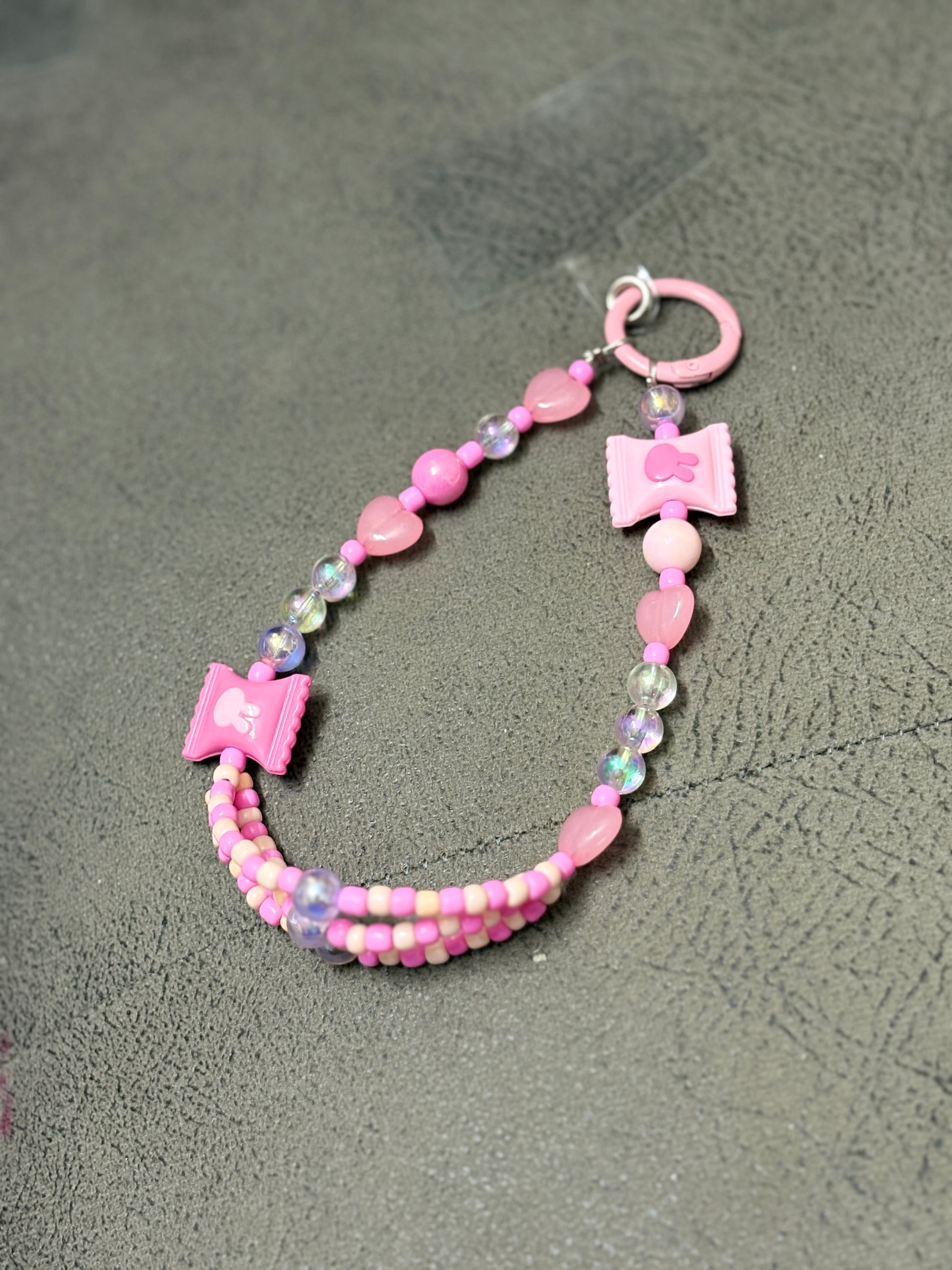 A set of handmade beaded phone charms featuring playful candy-shaped accents, heart beads, and glossy finishes, designed to accessorize phone cases with a fun and trendy touch.