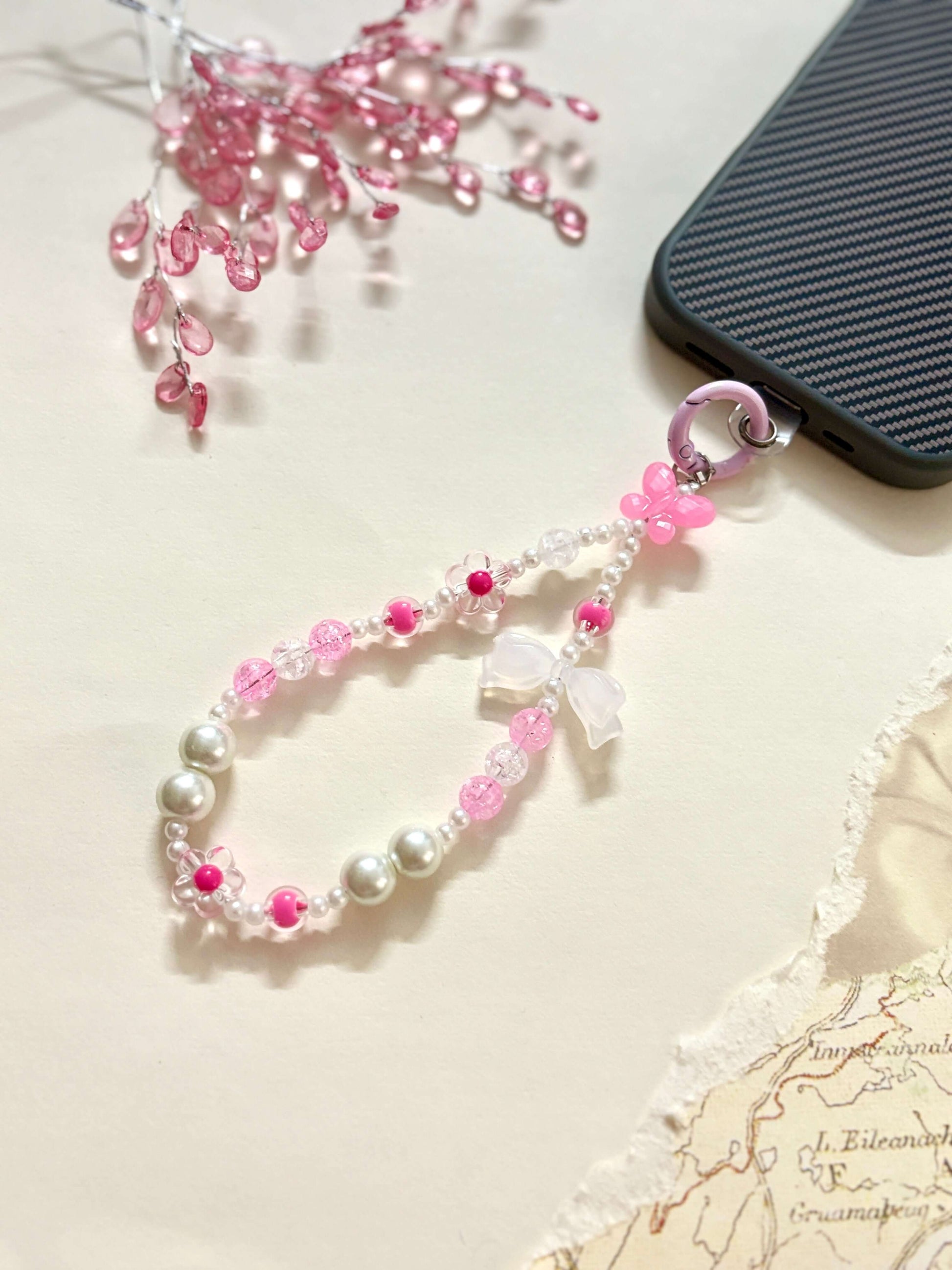Decorative beaded phone charm featuring heart, flower, and pearl-like beads with a mix of textures and finishes, designed as a stylish phone strap accessory.