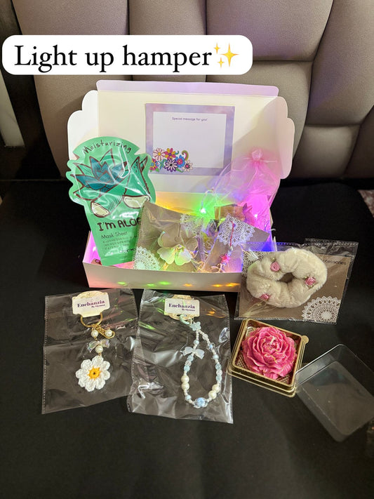 A curated gift hamper featuring fairy lights, a face mask, scented candle, scrunchie, big and small phone charms, crochet keychain, clutcher, toffees, and a message card — perfect for gifting and self-care.