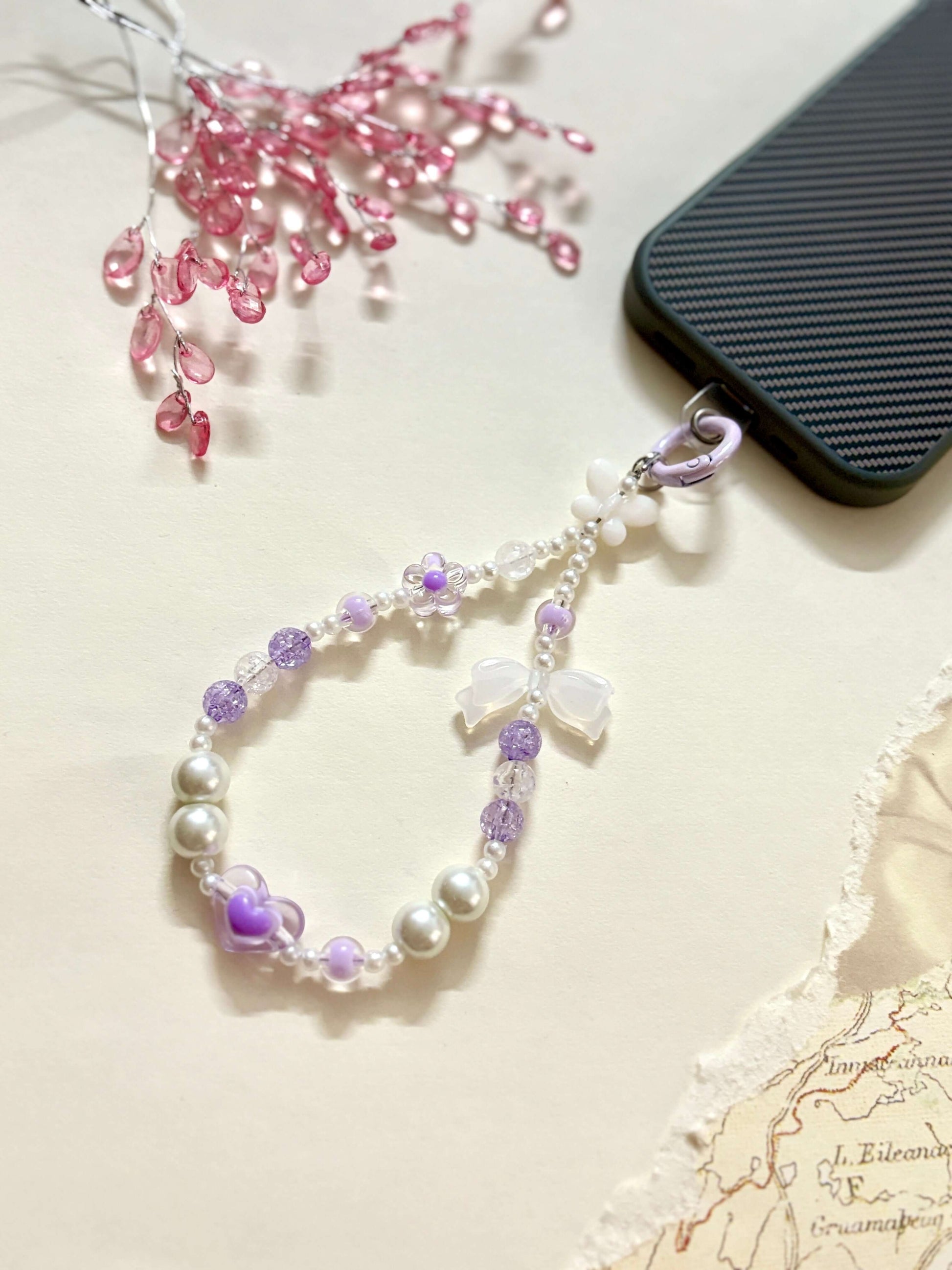 Decorative beaded phone charm featuring heart, flower, and pearl-like beads with a mix of textures and finishes, designed as a stylish phone strap accessory.